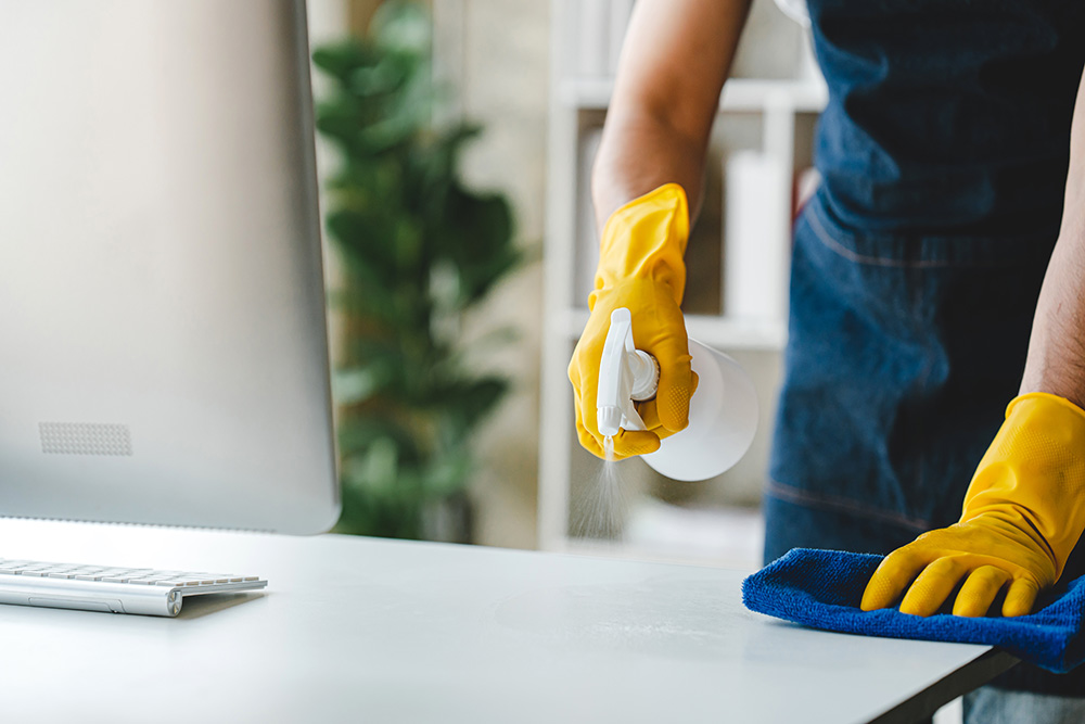 MMM Cleaning facility care specialist wiping down modern office furniture in Troy.